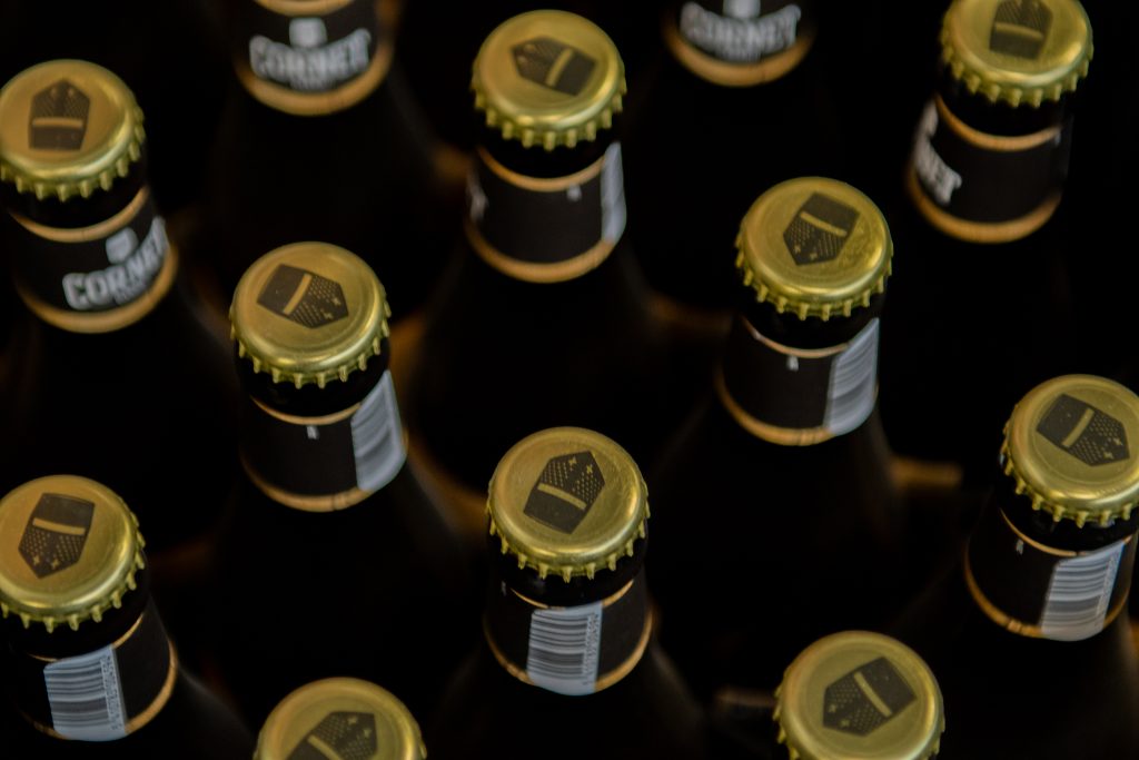 Close-up van gouden kroonkurken van Cornet-bierflessen in het assortiment van Dranken Vandenameele.