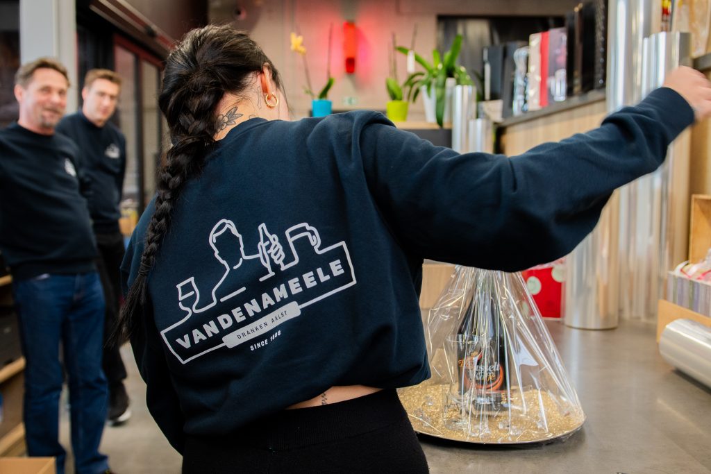 Medewerker van Dranken Vandenameele Aalst werkt aan een drankgeschenk in de winkel.