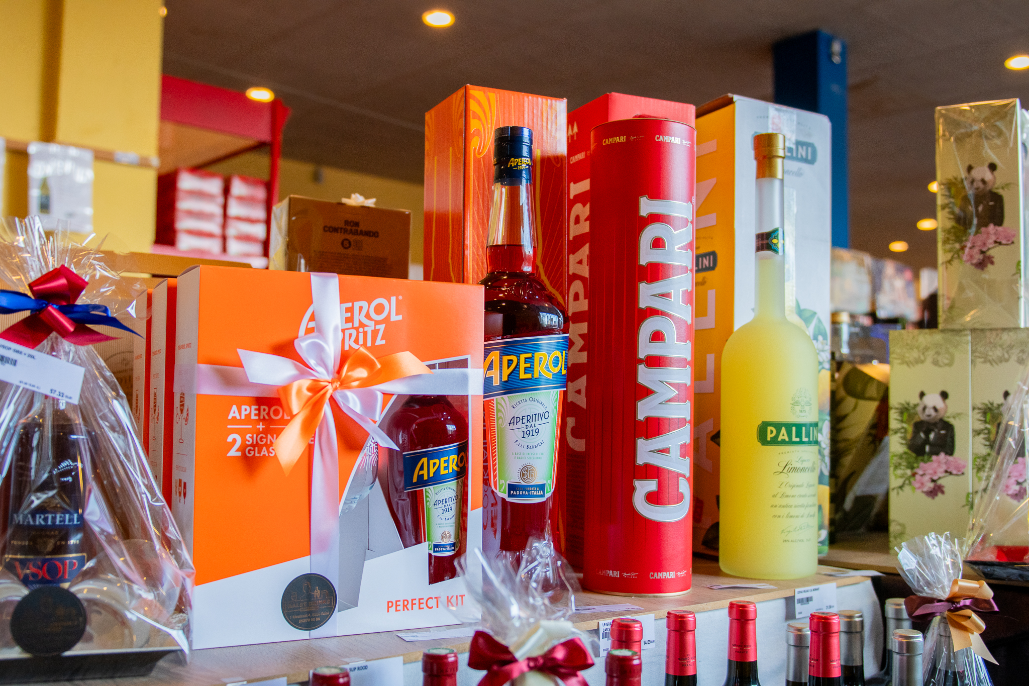 Aanbod van aperitieven en geschenkpakketten zoals Aperol, Campari en Pallini Limoncello in een winkel van Vandenameele.