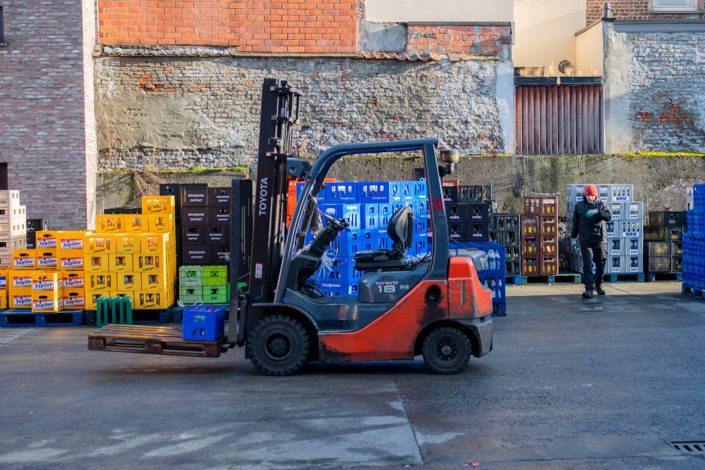 Medewerker van Dranken Vandenameele verplaatst drankkratten met een heftruck op de laadplaats.