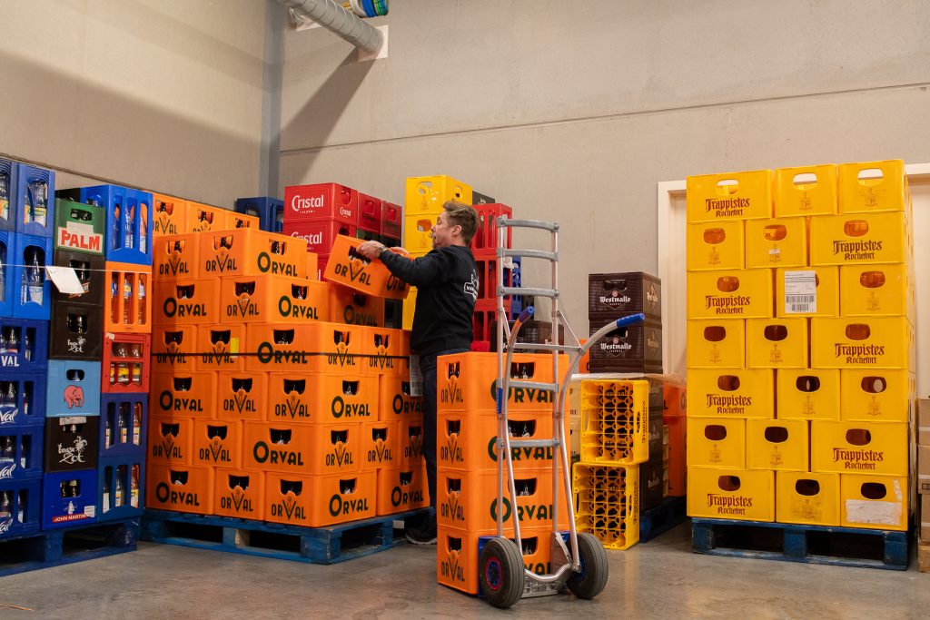 Een medewerker van Vandenameele sorteert kratten Orval en andere Belgische bieren in het magazijn.